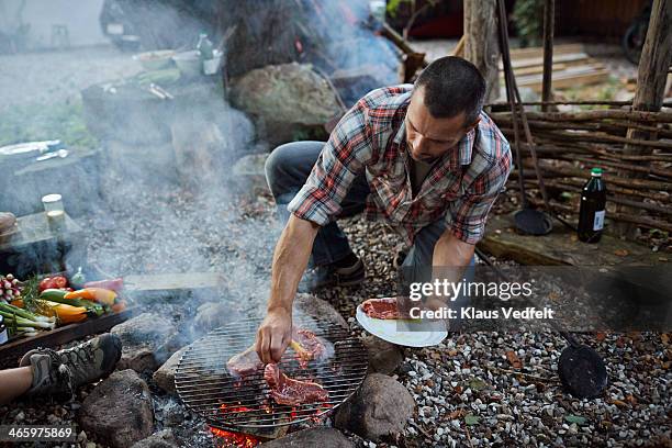 man putting meat on homemade grill - checked shirt stock-fotos und bilder