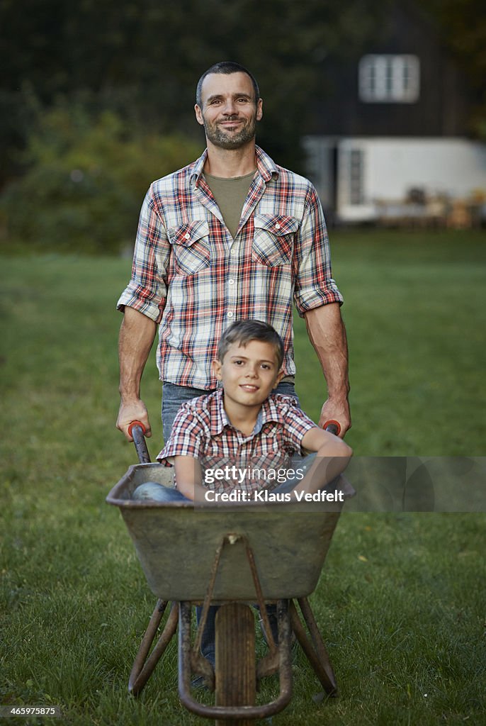 Father walking with son sitting in wheelbarrow