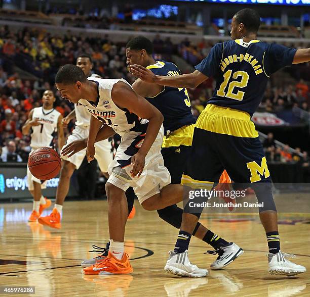 Malcolm Hill of the Illinois Fighting Illini drives between Kameron Chatman and Muhammad-Ali Abdur-Rahkman of the Michigan Wolverines during the...