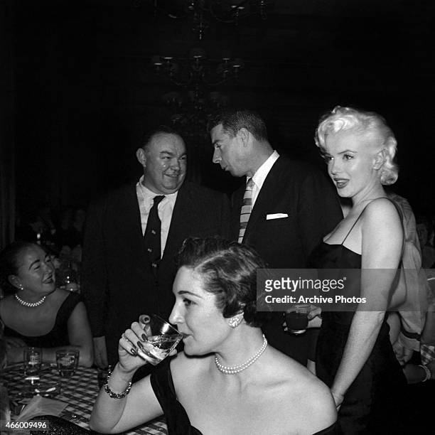 Actress Marilyn Monroe looks on as former husband Joe DiMaggio chats with a guest at Jackie Gleason's birthday party at Toots Shor's Restaurant on...