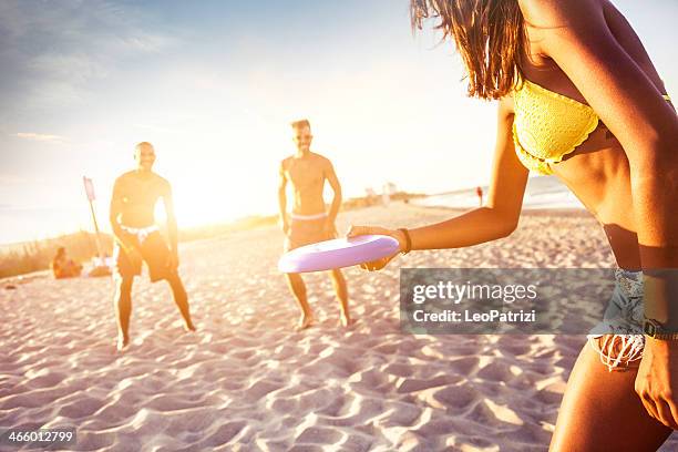 jugando en la playa con un freesbi - frisbee fotografías e imágenes de stock