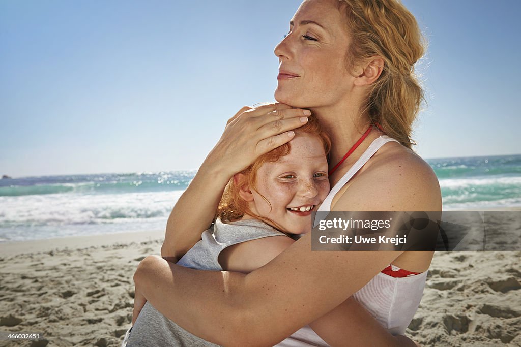 Mother and daughter hugging on beach