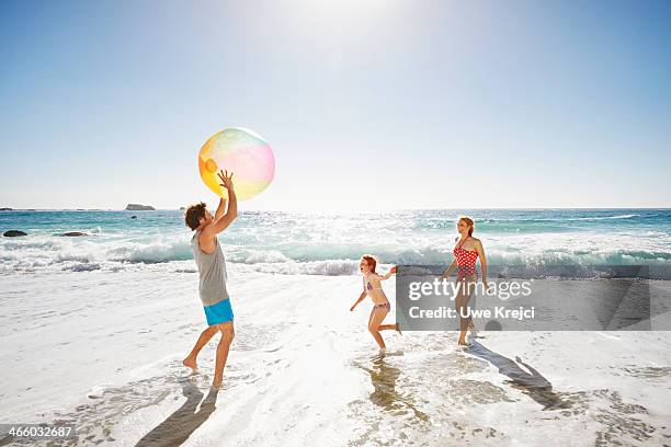 family playing with ball by the ocean - beach family stock pictures, royalty-free photos & images