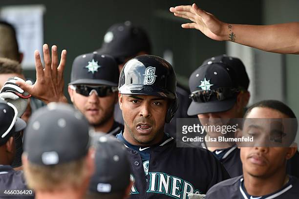 Nelson Cruz of the Seattle Mariners returns to the dugout after scoring against the Oakland Athletics at HoHoKam Stadium on March 12, 2015 in Mesa,...