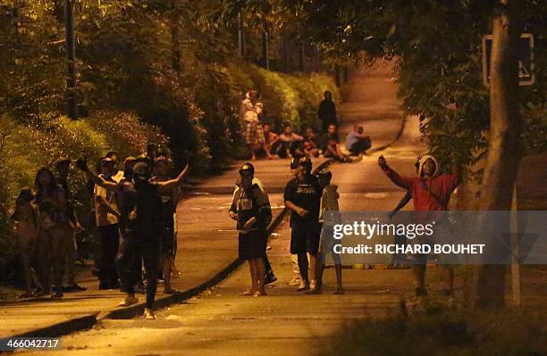 Youths gesture within clashes with police, unseen, on January 30, 2014 in the Chaudron district of Saint-Denis de La Reunion, French Indian Ocean....