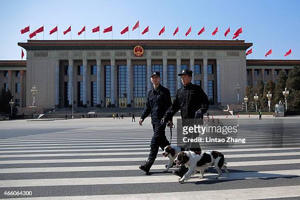 Two policeman leads police dogs guarding in front of the Great Hall of the People before the closing ceremony of the Chinese People's Political...