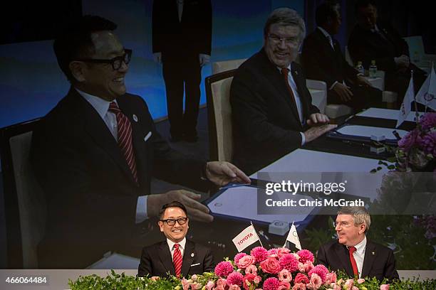 President and CEO of Toyota Motor Corporation, Akio Toyoda and President of the International Olympic Committee Thomas Bach joke around s they sign...