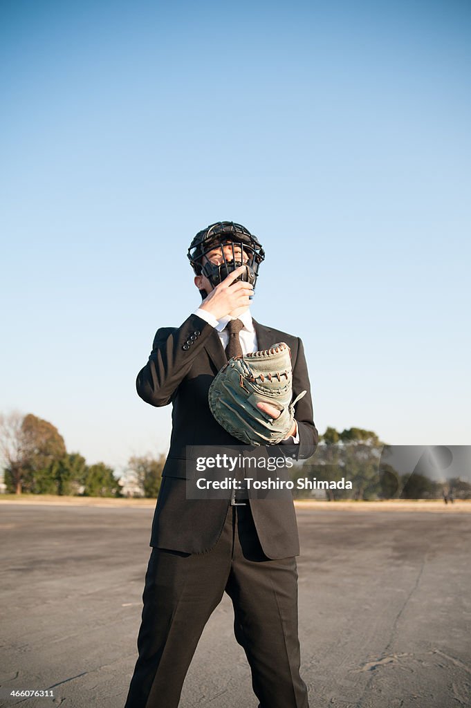 A suited man standing in backstop's equipment