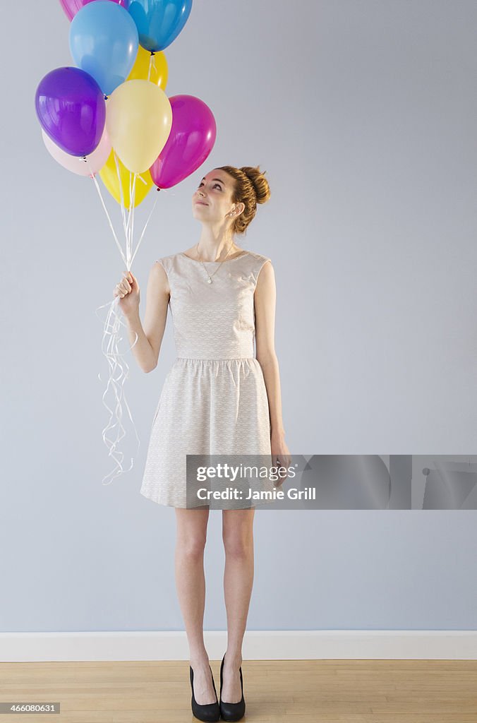 Woman holding bunch of balloons