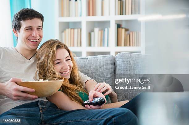 couple watching tv together - young couple watching tv stock pictures, royalty-free photos & images