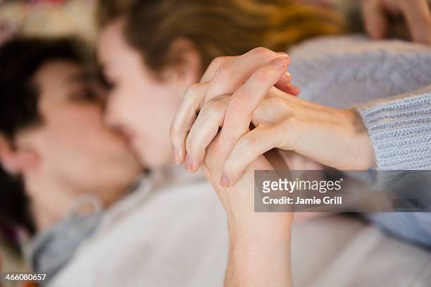 couple holding hands while kissing - two men in bed cuddling stock-fotos und bilder