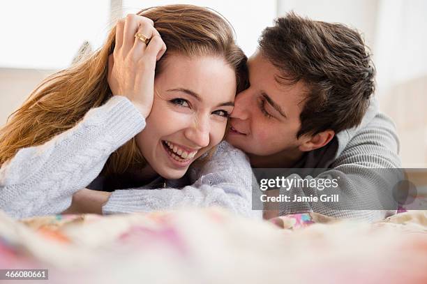 boyfriend kissing woman on cheek - man and woman kissing in bed stock pictures, royalty-free photos & images