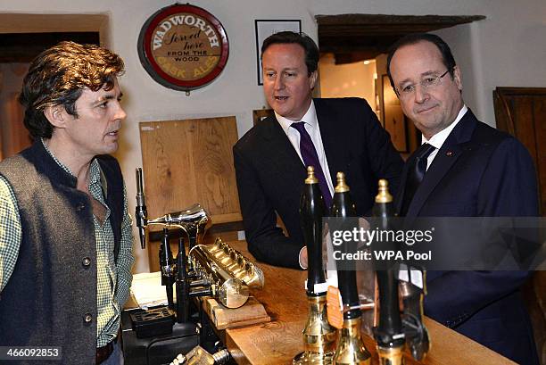 Britain's Prime Minister David Cameron and France's President Francois Hollande stand at the bar with landlord Archie Orr-Ewing as they arrive for an...