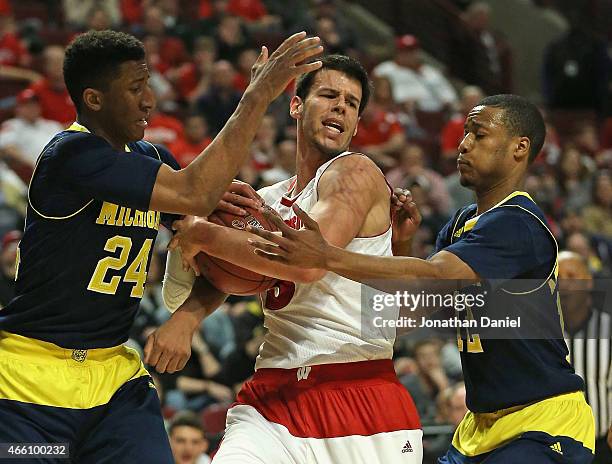 Duje Dukan of the Wisconsin Badgers tries to keep the ball away from Aubrey Dawkins and Muhammad-Ali Abdur-Rahkman of the Michigan Wolverines during...