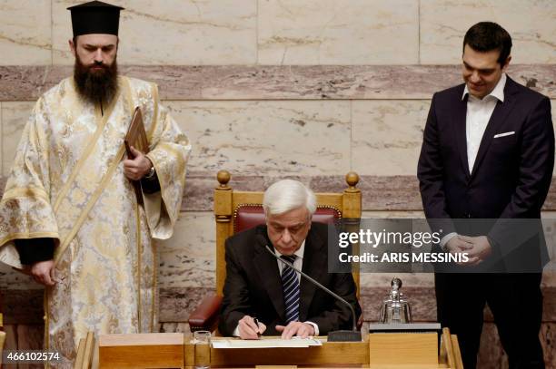 New Greek President Prokopis Pavlopoulos signs documents after taking the oath of office as Greek Prime Minister Alexis Tsipras looks on during a...