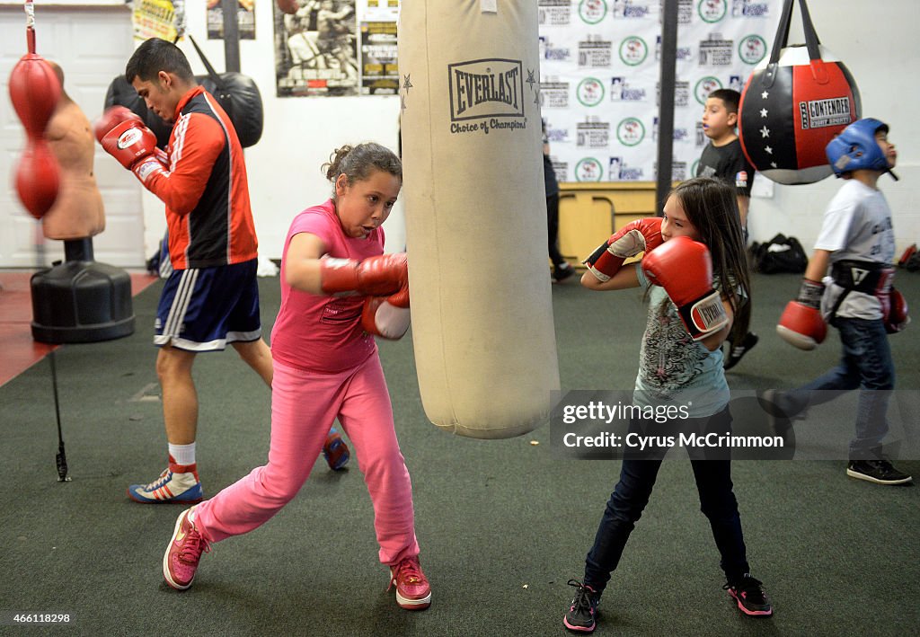 Surrounded by young boxers, Golden Gloves boxer Julio Para, left, works the double end bag as he trains at the Colorado Golden Gloves Gym.