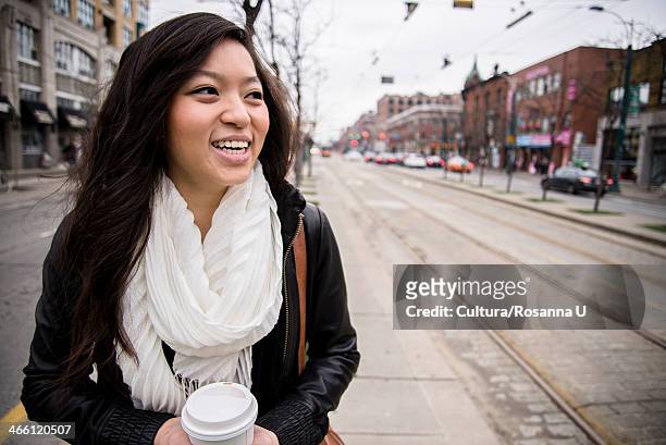 young woman walking on street in city, smiling - cultura orientale photos et images de collection