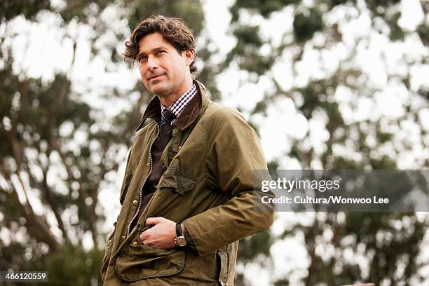 mid adult man in countryside, looking away - waxed jacket stock pictures, royalty-free photos & images