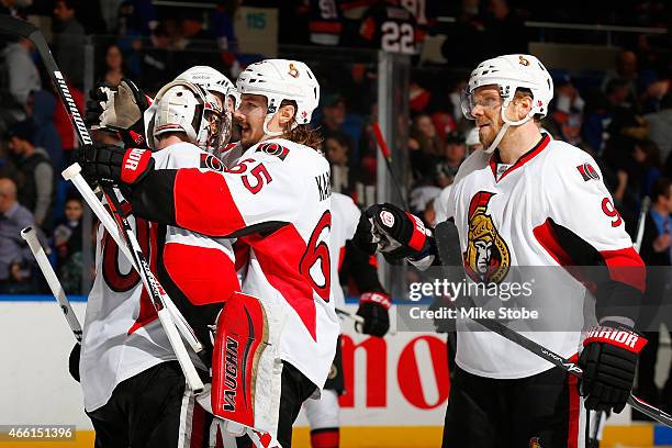 Andrew Hammond of the Ottawa Senators is congratulated by his teammates Milan Michalek and Erik Karlsson after defeating the New York Islanders at...