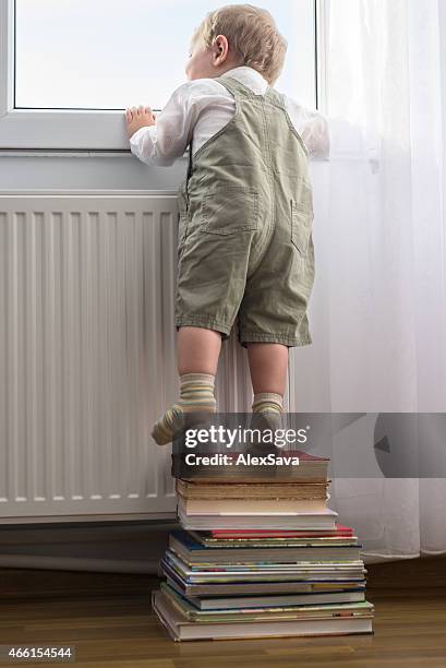 young boy looking outside the window - resourceful stock pictures, royalty-free photos & images