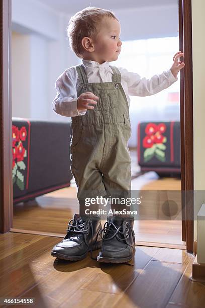 young boy standing in his father's shoes by the doorway - baby boot stock pictures, royalty-free photos & images