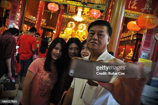 Temple-goers pose for a family portrait at a shrine in Chinatown during festivities welcoming in the Chinese New Year on January 31, 2014 in Bangkok,...