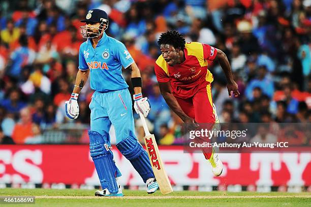 Solomon Mire of Zimbabwe bowls as Virat Kohli of India looks on during the 2015 ICC Cricket World Cup match between India and Zimbabwe at Eden Park...