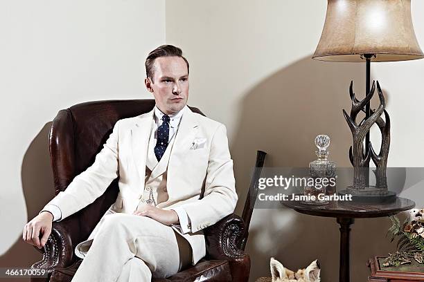 man in cream suit sitting in chair with whisky. - cream coloured suit stock-fotos und bilder