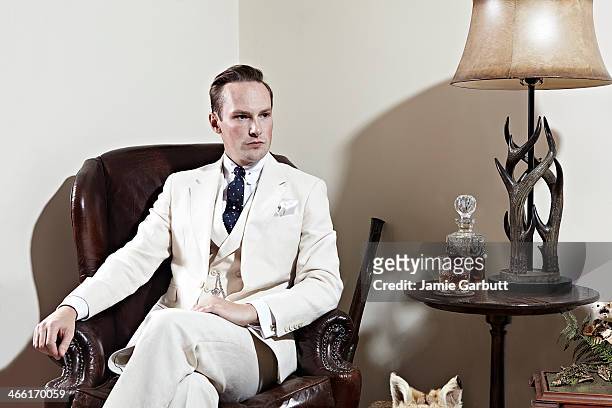 man in cream suit sitting in chair with whisky. - old fashioned whiskey stock pictures, royalty-free photos & images