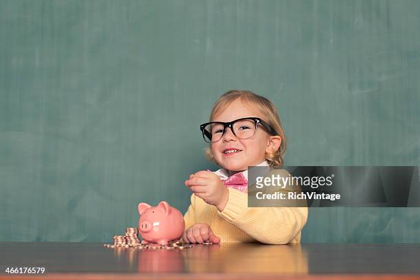junges mädchen mit brille spart geld im sparschwein - wit blackboard stock-fotos und bilder