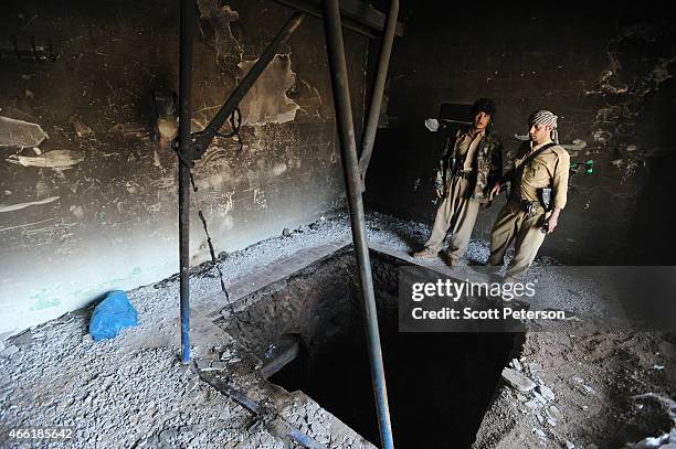 Peshmerga fighters examine the entrance to a 150-meter-long tunnel dug by ISIS in a village once controlled by ISIS as Iraqi Kurdish forces push the...