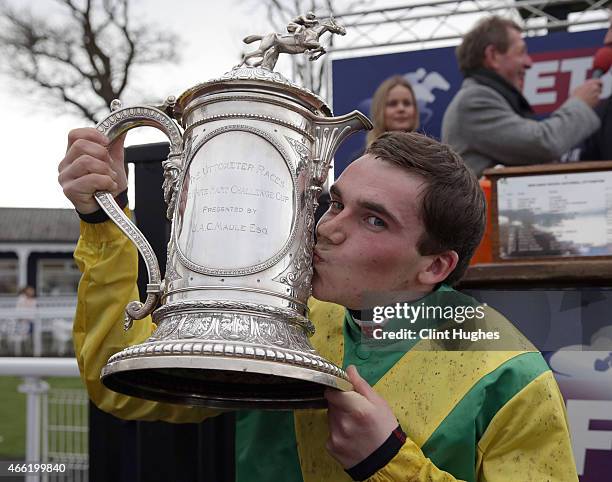 Jonathan Burke celebrates with the White Heart Challenge Cup after winning the Betfred Midlands Grand National Steeple Chase at Uttoxeter Racecourse...