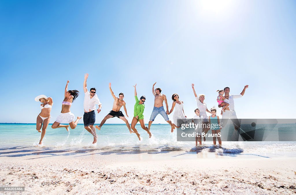 Grupo grande de Alegre personas salto en la playa.