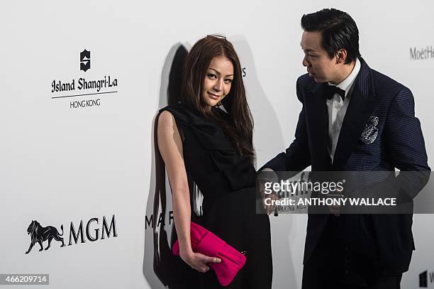 Leung Chai-yan, daughter of Hong Kong Chief Executive Leung Chun-ying, is escorted by an unidentified attendant as she poses on the red carpet during...