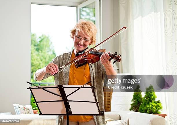 senior woman playing violin at home - violin family stock pictures, royalty-free photos & images