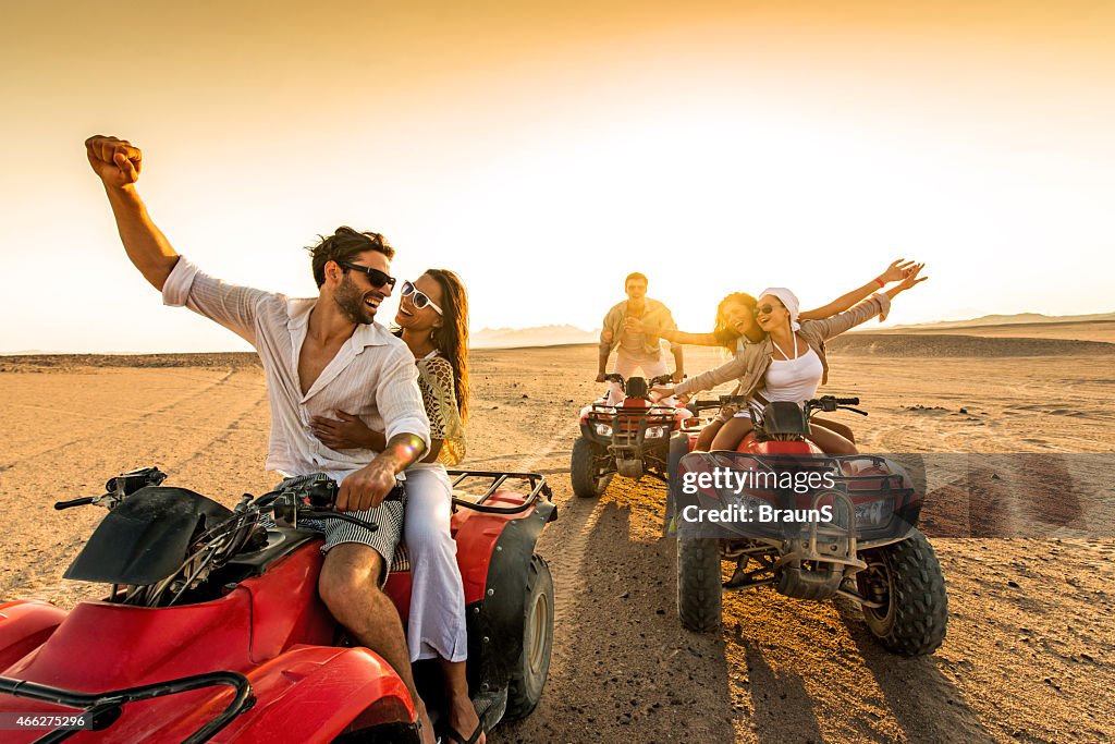 Friends having fun riding quad bikes in desert