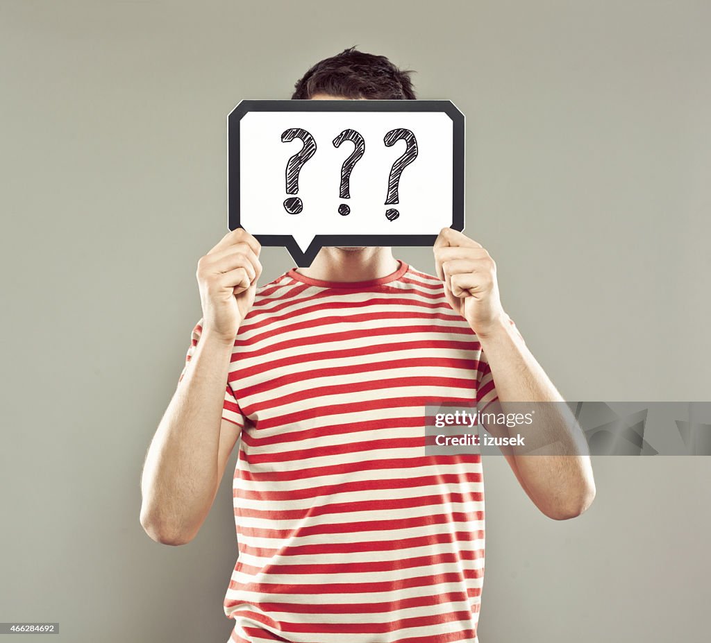Young man holding speech bubble with question marks