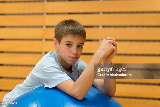 portrait, eleven years old boy with exercise ball, school gymnasium - 10 years stockfoto's en -beelden