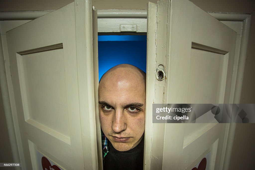 Creepy bald Man Staring At Camera through the door