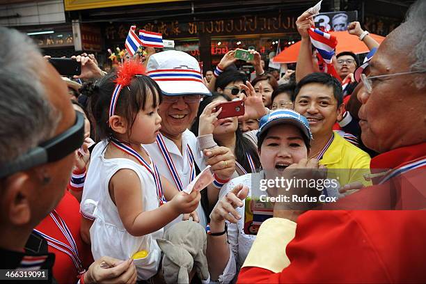 Anti-government protest leader Suthep Thaugsuban is greeted by supporters and given cash donations while marching through Chinatown on February 1,...