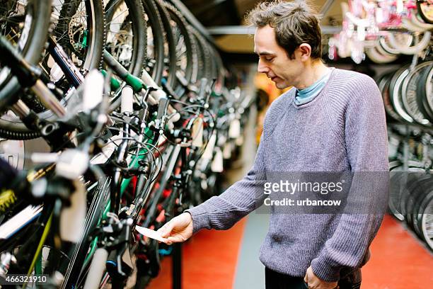 customer in a bicycle shop, looking at the price tag - bike shop stock pictures, royalty-free photos & images