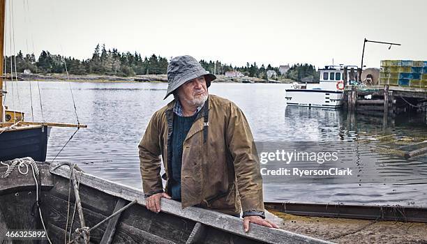 fisherman standing near a dory, mahone bay, nova scotia - vintage sailor stock pictures, royalty-free photos & images