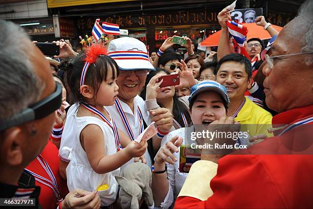 Anti-government protest leader Suthep Thaugsuban is greeted by supporters and given cash donations while marching through Chinatown on February 1,...