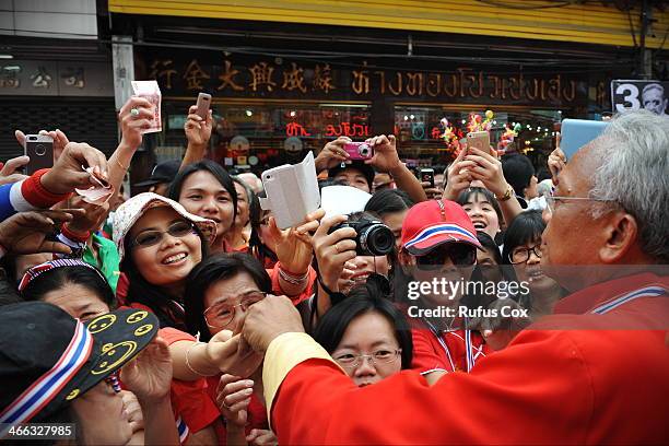 Anti-government protest leader Suthep Thaugsuban is greeted by supporters and given cash donations while marching through Chinatown on February 1,...