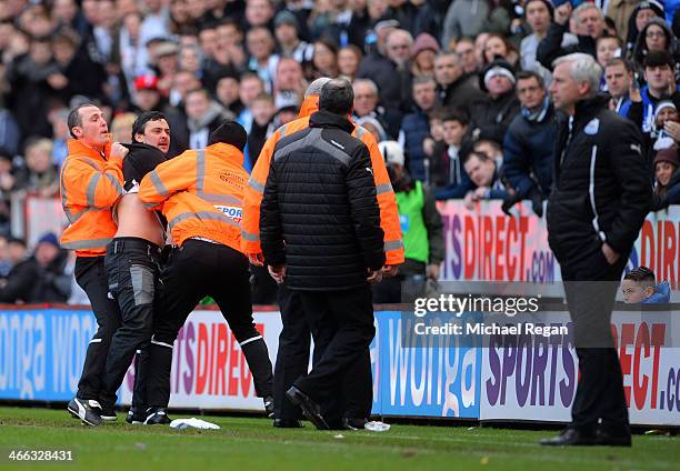 Disgruntled Newcastle fan shouts at Alan Pardew the Newcastle manager as he is removed from the pitch by stewards during the Barclays Premier League...