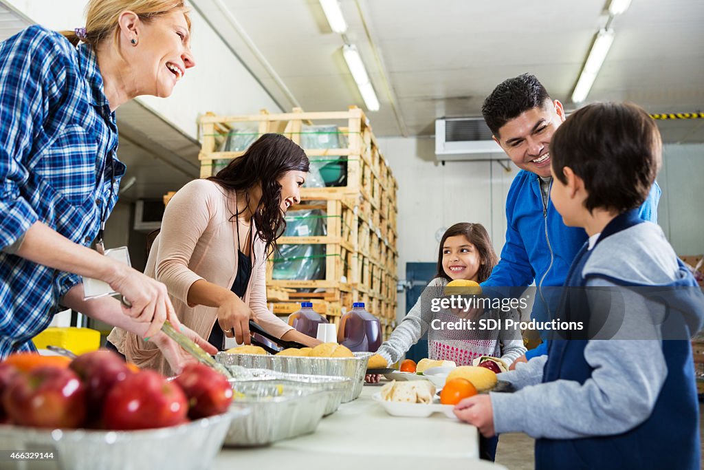 Happy volunteers talking to family in line at food bank