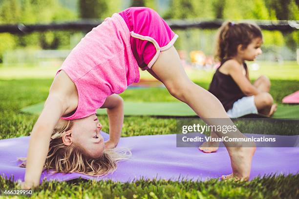 little girls doing yoga on mats in a park - children yoga stock pictures, royalty-free photos & images