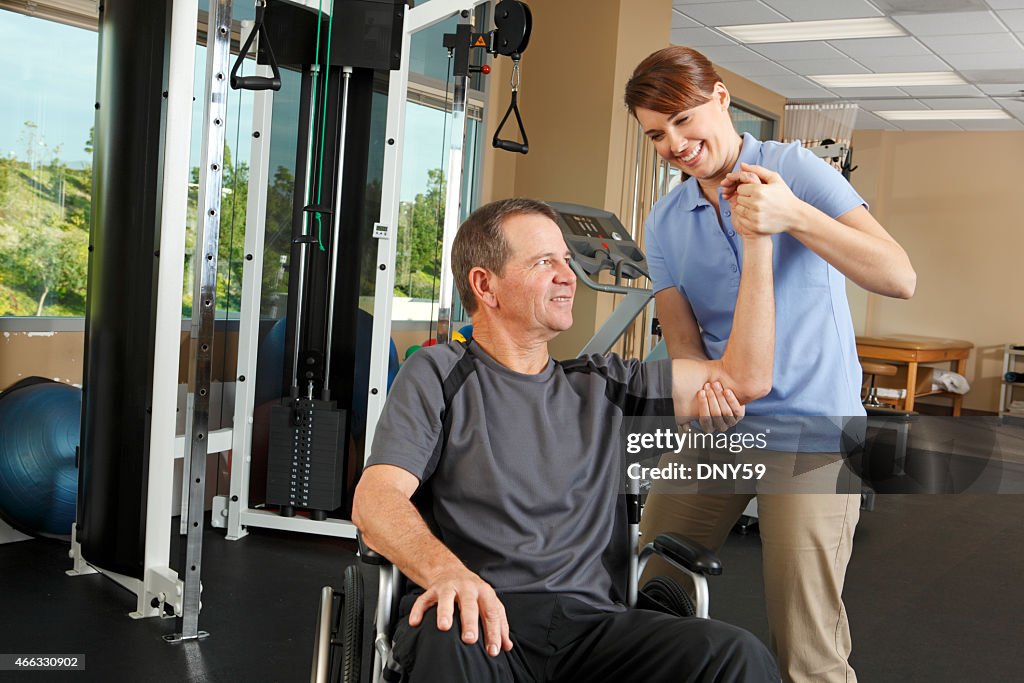 Physical therapist evaluating range of motion of patient in wheelchair