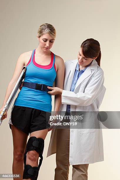 physical therapist using gait belt to help knee injury patient - knee brace stock pictures, royalty-free photos & images