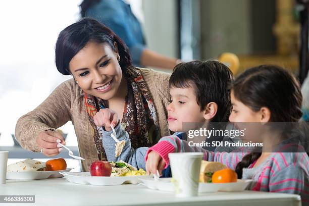 mother and young children having meal in charity soup kitchen - hot moms club stock pictures, royalty-free photos & images